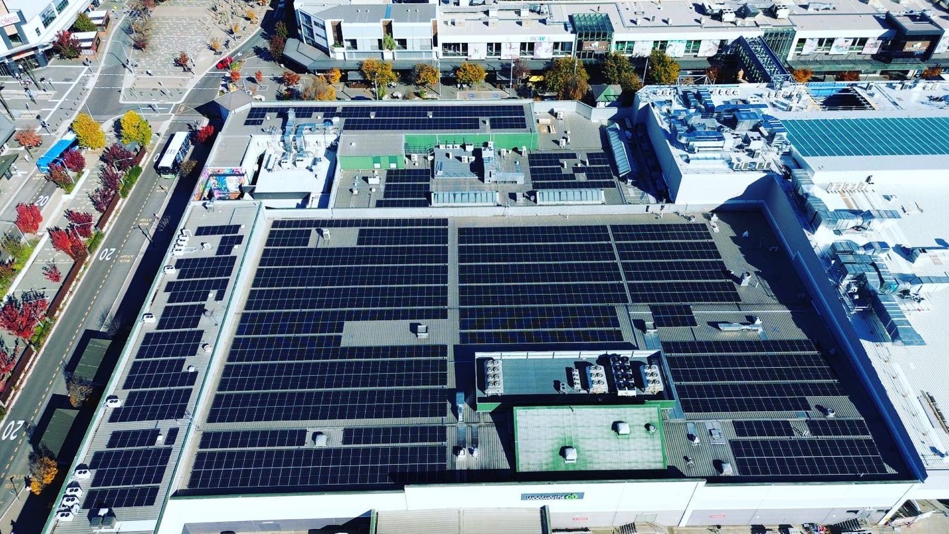Aerial of a large commercial rooftop Solar PV array beside a logistics yard