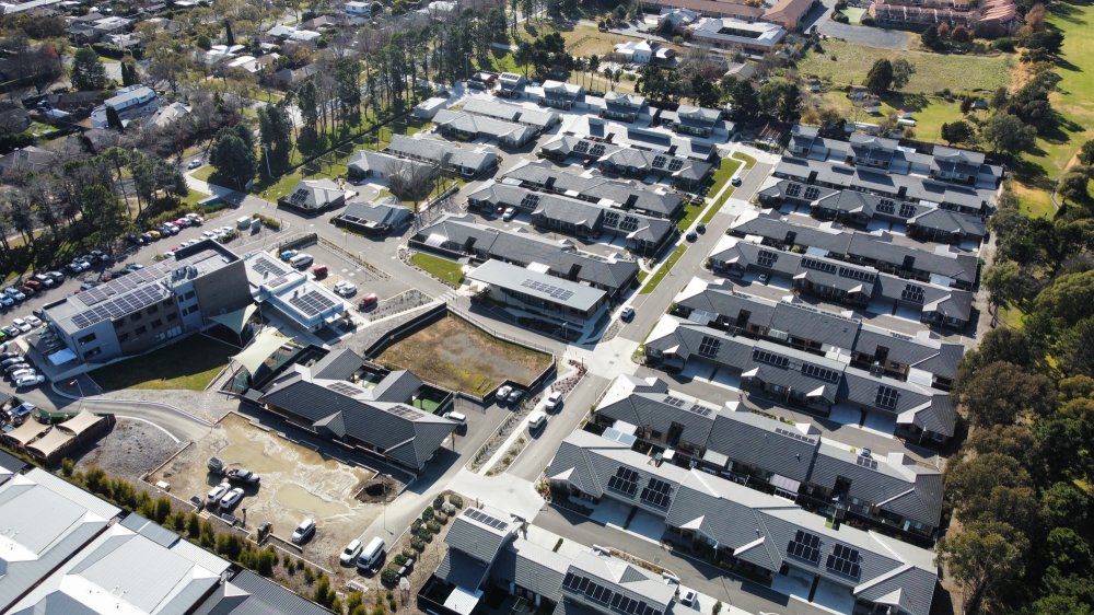 Aerial of the Marymead site in Canberra, rooftop solar spread across community buildings and a cluster of individual units